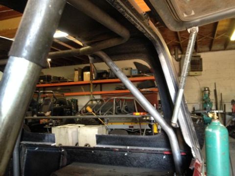 1985 Jeep CJ7 - Interior view of a vehicle's roll cage and dashboard, with workshop items visible.