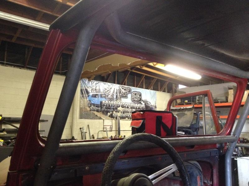 1985 Jeep CJ7 interior showing roll cage, steering wheel, and red tool bag