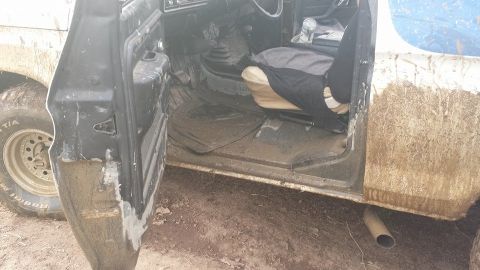 1979 Ford Bronco - Interior view of a muddy off-road vehicle with the driver's side door open.