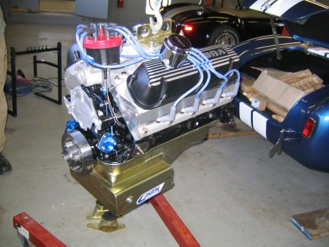 1978 Ford Bronco - A built Ford small-block V8 hanging on a hoist in a shop, wearing finned Cobra-lettered aluminum valve covers, a red distributor cap with l…
