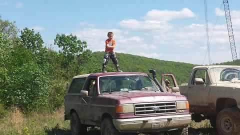 1979 Ford Bronco - Child stands atop a Ford Bronco, with another truck visible in the background on a sunny day.