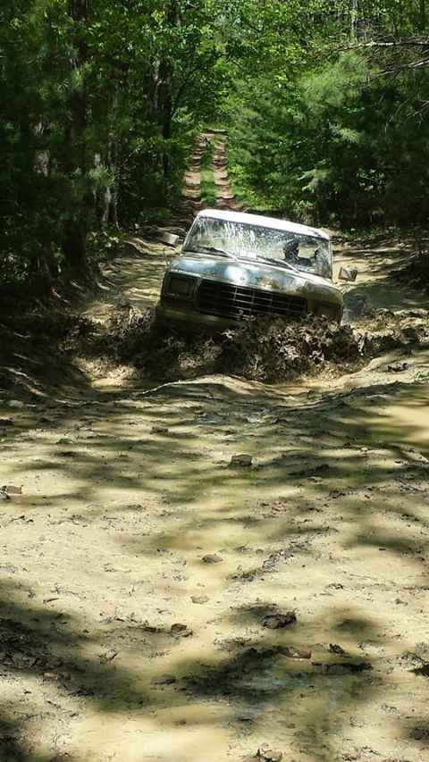 1979 Ford Bronco - A vehicle navigates a muddy trail, kicking up water and dirt as it goes.