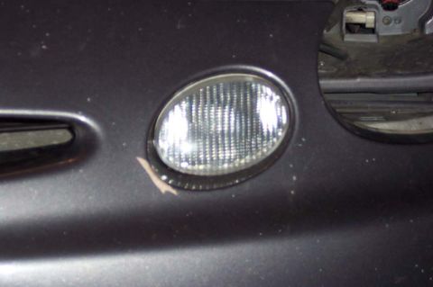 1996 Ford Taurus - Close-up of a car's front bumper shows a fog light and a website logo.
