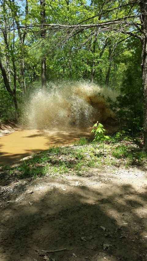 1979 Ford Bronco - Off-road vehicle creating a large mud splash while driving through a puddle.