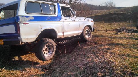 1979 Ford Bronco - This 1979 Ford Bronco is captured in a three-quarter front view as it navigates a grassy, uneven terrain.