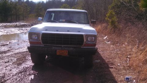 1979 Ford Bronco - This 1979 Ford Bronco is captured from the front, navigating a muddy off-road path.