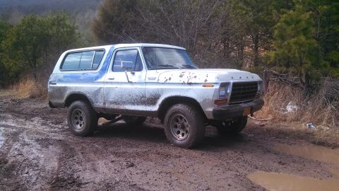 1979 Ford Bronco - Mud-splattered Ford Bronco navigates a wet, wooded trail.