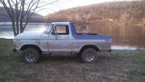 1979 Ford Bronco - A weathered 1978 Ford Bronco sits by the water, its exterior covered in mud.