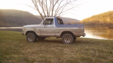 1979 Ford Bronco - Side view of a 1978 Ford Bronco parked by a river with trees and hills in the background.