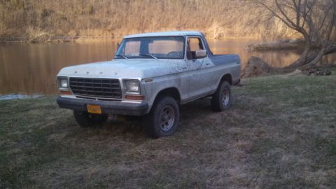 1979 Ford Bronco - A dusty gray 1978 Ford Bronco sits by the water's edge under a bare tree.