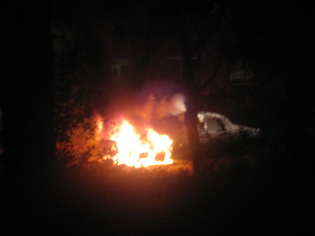 Vehicle on fire at night with bright flames and smoke in darkness