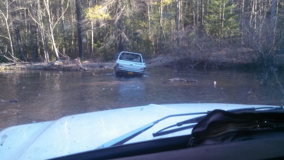 White pickup truck partially submerged in water, seen from inside another vehicle