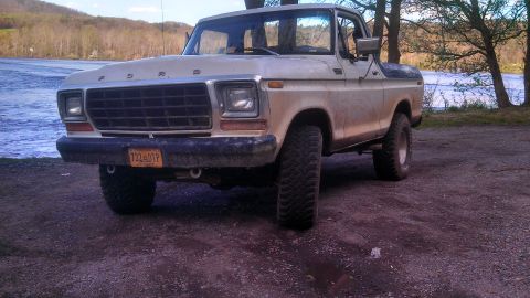 1979 Ford Bronco - This 1978 Ford Bronco is parked near a lake with trees and hills in the distance.