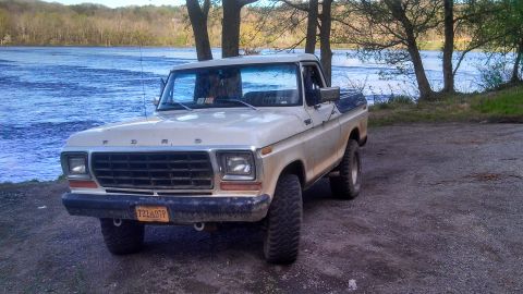 1979 Ford Bronco - This 1977 Ford F-150 pickup truck is parked by the water, showing its front and side profile.