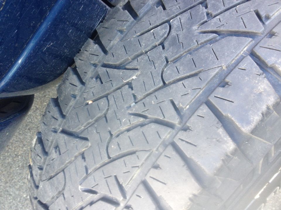 Close-up of a tire tread pattern with blue vehicle paint visible on the left