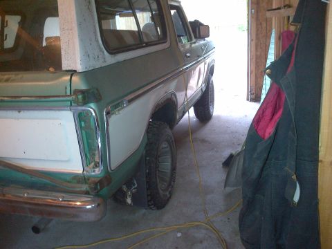 1978 Ford Bronco - The rear quarter panel of a classic Ford Bronco is visible, showing its two-tone paint scheme and chrome bumper.
