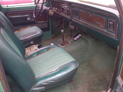 1978 Ford Bronco - The interior of a vehicle shows worn green seats and a dashboard with a "RANGER XLT" badge.