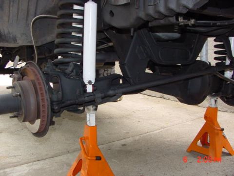 1992 Ford Bronco - Close-up view of the front suspension and axle assembly of a 1992 Ford Bronco, supported by orange jack stands.