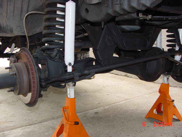 Twin-Traction Beam front suspension underside with coil spring, white shock and bare brake rotor