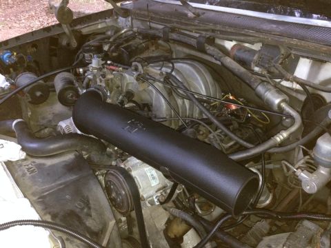1988 Ford Bronco - Close-up of an engine bay, showing various parts and wiring, with a prominent black intake tube.