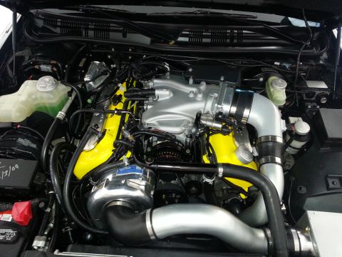 2003 Mercury Marauder - Close-up of a modified V8 engine a prominent supercharger and bright yellow valve covers.