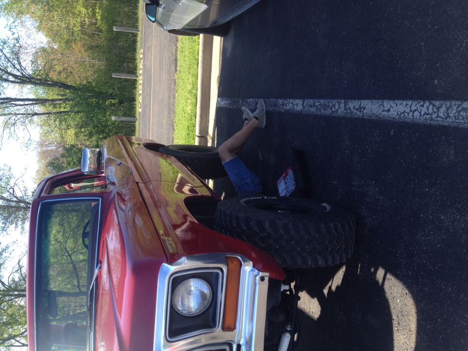 1978 Ford Bronco with person underneath working on the front wheel