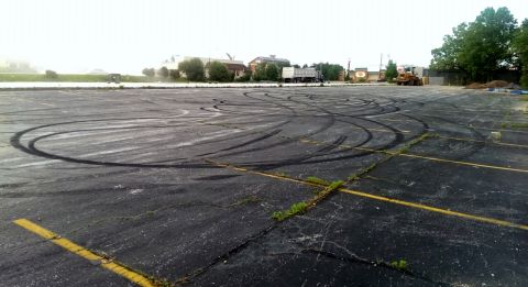 2000 Mercury Grand Marquis - An empty asphalt lot shows extensive tire marks, indicating recent vehicle activity.