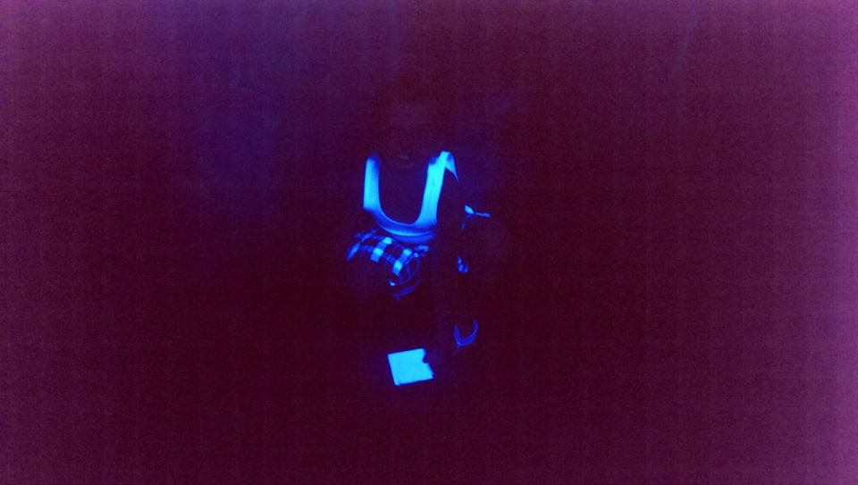 Car interior lit by blacklight, showing glowing blue accents on seats and dashboard