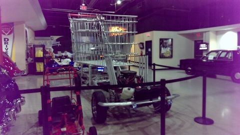 2000 Mercury Grand Marquis - A unique vehicle, resembling a giant shopping cart, is displayed indoors with other vehicles nearby.