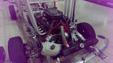 2000 Mercury Grand Marquis - A custom hot rod chassis is shown with its V8 engine, prominent exhaust pipes, and front suspension components visible.