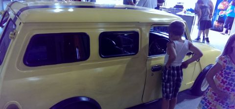 2000 Mercury Grand Marquis - A yellow van with a distinctive roofline and side windows is viewed from the side, with two children observing it.