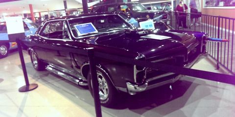 2000 Mercury Grand Marquis - A black 1966 Pontiac GTO is displayed indoors with a blue sign on the dashboard.