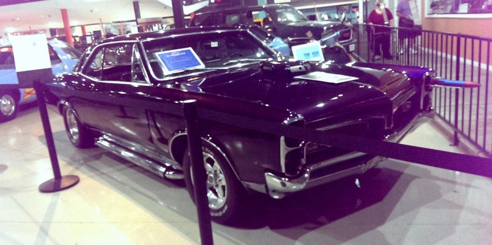Black 1966 Pontiac GTO coupe with chrome side pipes and aftermarket wheels