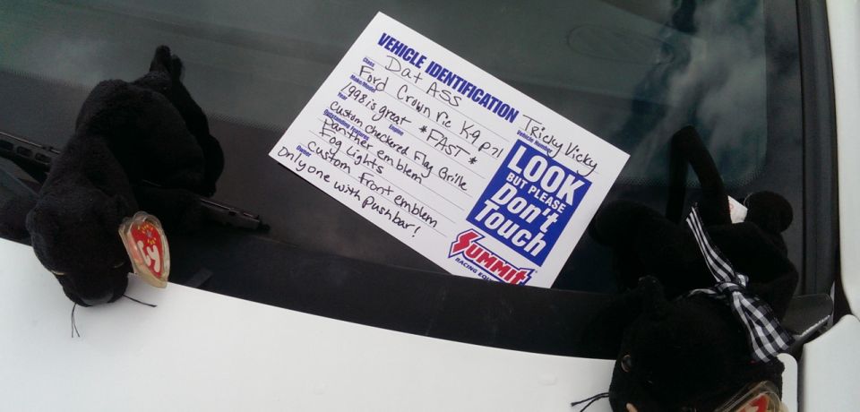 Handwritten Vehicle Identification card placed under a windshield wiper with plush toys nearby