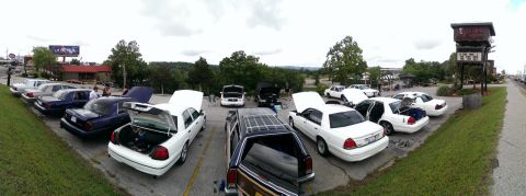 2000 Mercury Grand Marquis - A gathering of Mercury Grand Marquis sedans, many with their hoods and trunks open, parked in a lot.
