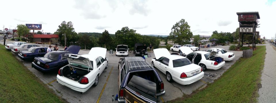 Several white Mercury Grand Marquis sedans parked in a lot with hoods and trunks open