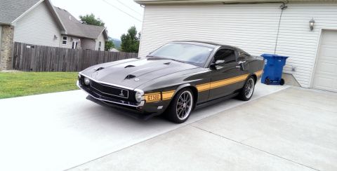 2000 Mercury Grand Marquis - A classic 1969 Shelby GT500 Mustang is parked in front of a garage.