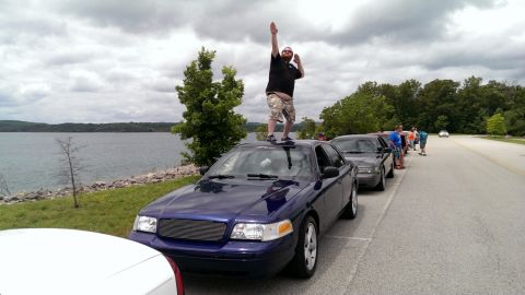 2000 Mercury Grand Marquis - Man stands atop a 2000 Mercury Grand Marquis during a car meet by the water.