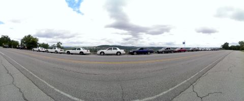 2000 Mercury Grand Marquis - A row of Mercury Grand Marquis sedans are parked along a scenic overlook, likely during a car show or gathering.