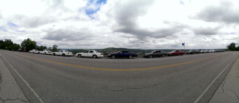 Line of 2000 Mercury Grand Marquis sedans parked on a scenic overlook, cloudy sky