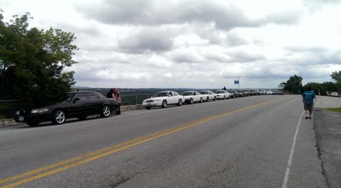 2000 Mercury Grand Marquis - A long line of sedans are parked along the side of a road at a scenic overlook.