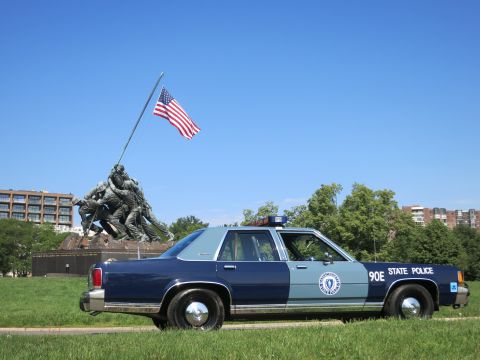 1991 Ford LTD Crown Victoria - Rear-quarter view of a blue-and-gray Massachusetts State Police Ford sedan, unit 90E, parked near the Iwo Jima Memorial.