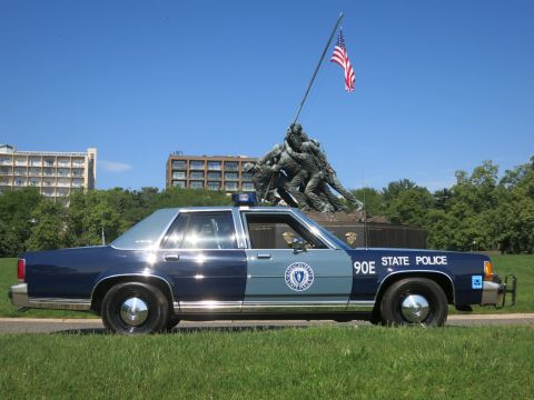 1991 Ford LTD Crown Victoria - blue-and-gray Massachusetts State Police Ford sedan, unit 90E, with a front push bar, parked before the Iwo Jima Memorial.