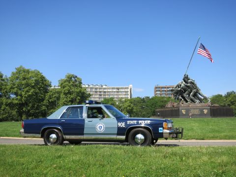 1991 Ford LTD Crown Victoria - blue-and-gray Massachusetts State Police Ford sedan, unit 90E, with a front push bar, parked before the Iwo Jima Memorial.