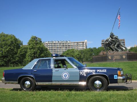 1991 Ford LTD Crown Victoria - blue-and-gray Massachusetts State Police Ford sedan, unit 90E, parked on grass with the Iwo Jima Memorial in the background.