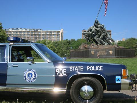 1991 Ford LTD Crown Victoria - Close front-quarter view of a Massachusetts State Police Ford sedan, unit 90E, showing the door seal and STATE POLICE lettering near the Iw…
