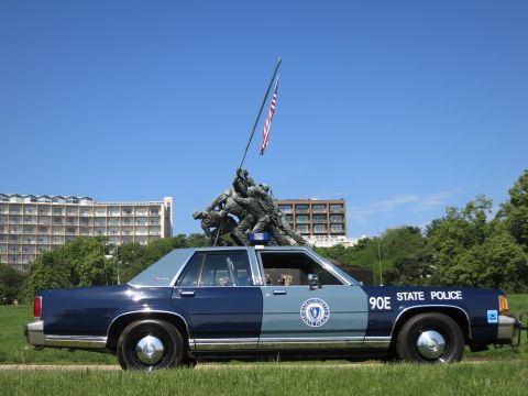 1991 Ford LTD Crown Victoria - navy and pale-blue State Police cruiser sits directly below the towering Marine Corps flag-raising memorial.