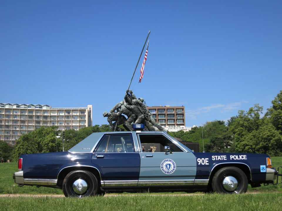 Side view of two-tone blue Massachusetts State Police 90E sedan beneath the Iwo Jima Memorial