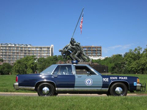 1991 Ford LTD Crown Victoria - Profile of a two-tone blue State Police sedan with the Marine Corps War Memorial statue directly overhead.