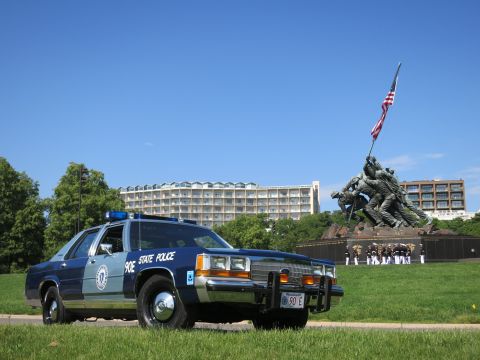 1991 Ford LTD Crown Victoria - two-tone blue State Police cruiser before the Marine Corps memorial, with a cluster of uniformed personnel behind it.